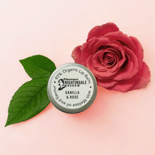 a metal tin of lip balm with a pink rose next to it