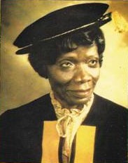 colour photograph of a lady, smiling and looking off the the right. She is wearing a black cap and robe.
