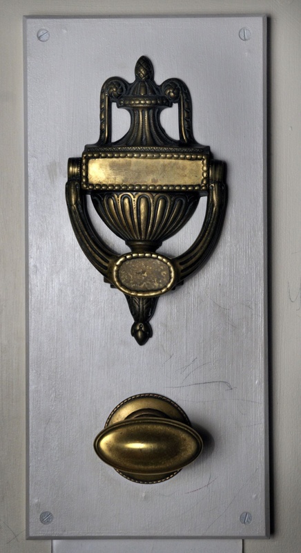Ornate brass door knocker. Curved handle with lots of fluting and carved details.
