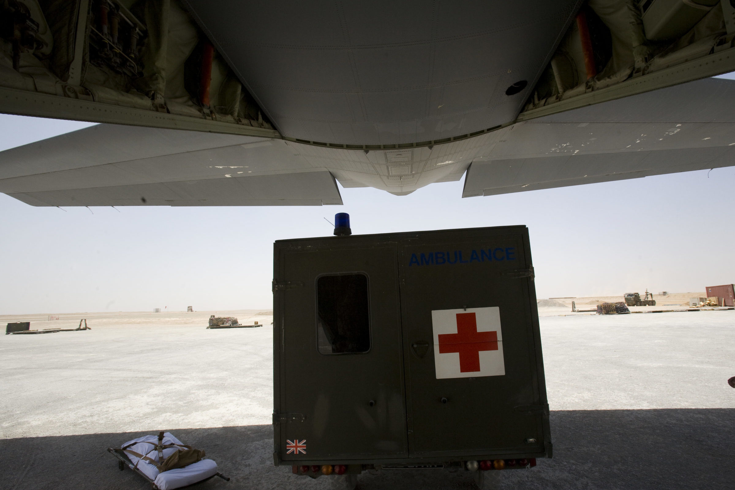 Military ambulance beside plane on a runway, Camp Bastion Hospital in Afghanistan