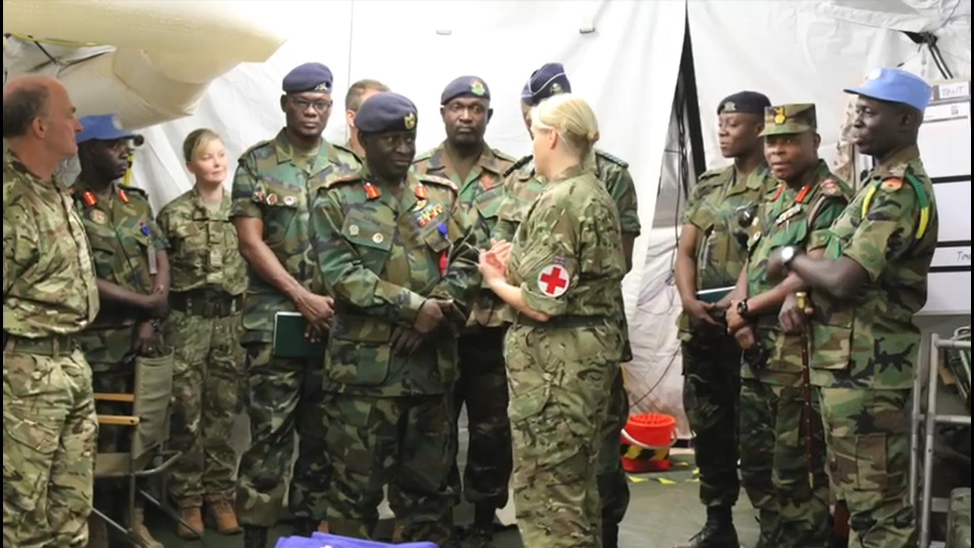 Nurses in armed forces uniform talk in a tented hospital