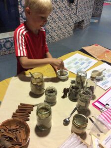 a young child uses a pestle and mortar to mix together herbs