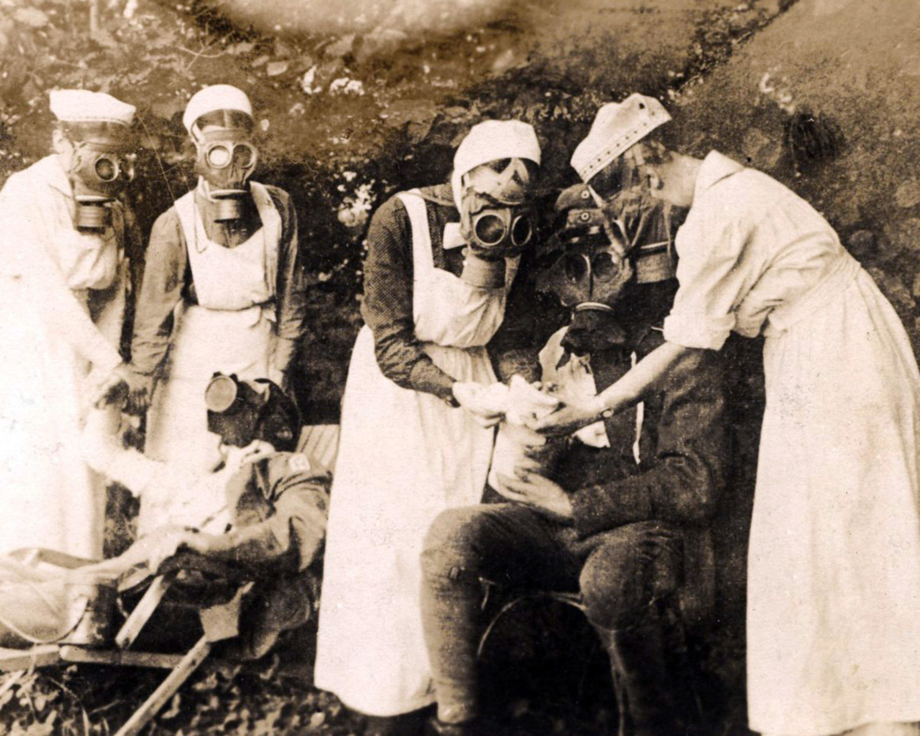 Nurses wearing gas masks tend a soldier patient in World War One photo