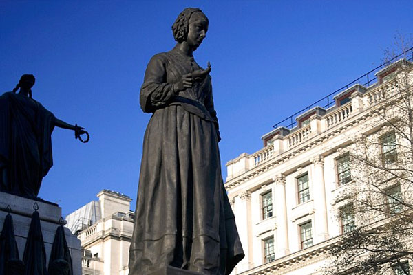 A metal statue of Florence Nightingale holding a lamp.